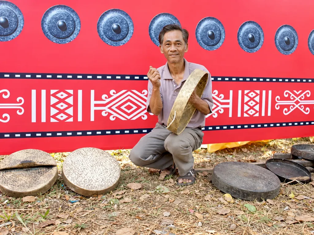Ảnh nghệ nhân/thợ Phước Kiều bên bộ cồng chiêng hoàn thiện